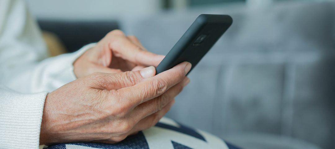 Agendamento digital: mãos de uma pessoa idosa segurando um celular smartphone