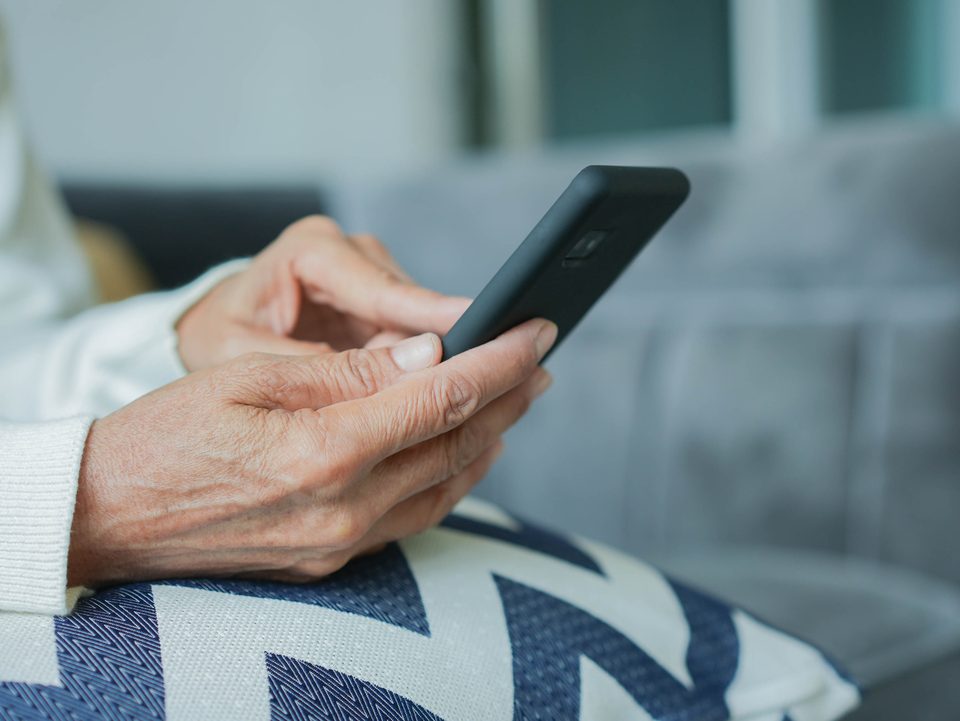 Agendamento digital: mãos de uma pessoa idosa segurando um celular smartphone