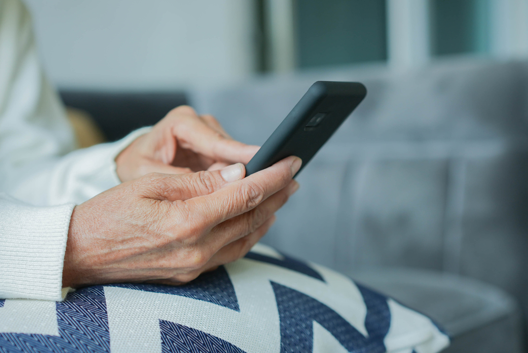 Agendamento digital: mãos de uma pessoa idosa segurando um celular smartphone